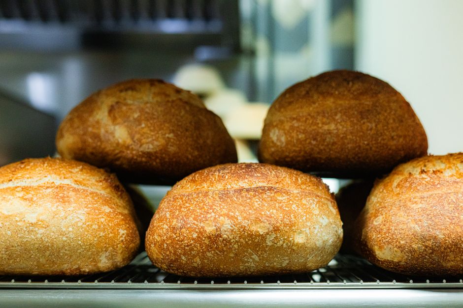 Loaves cooling on a wooden rack beside the hearth